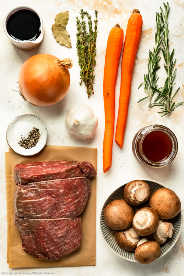 Overhead photo of all the ingredients needed to make eye of round roast beef recipe neatly organized by individual ingredient on a white surface.