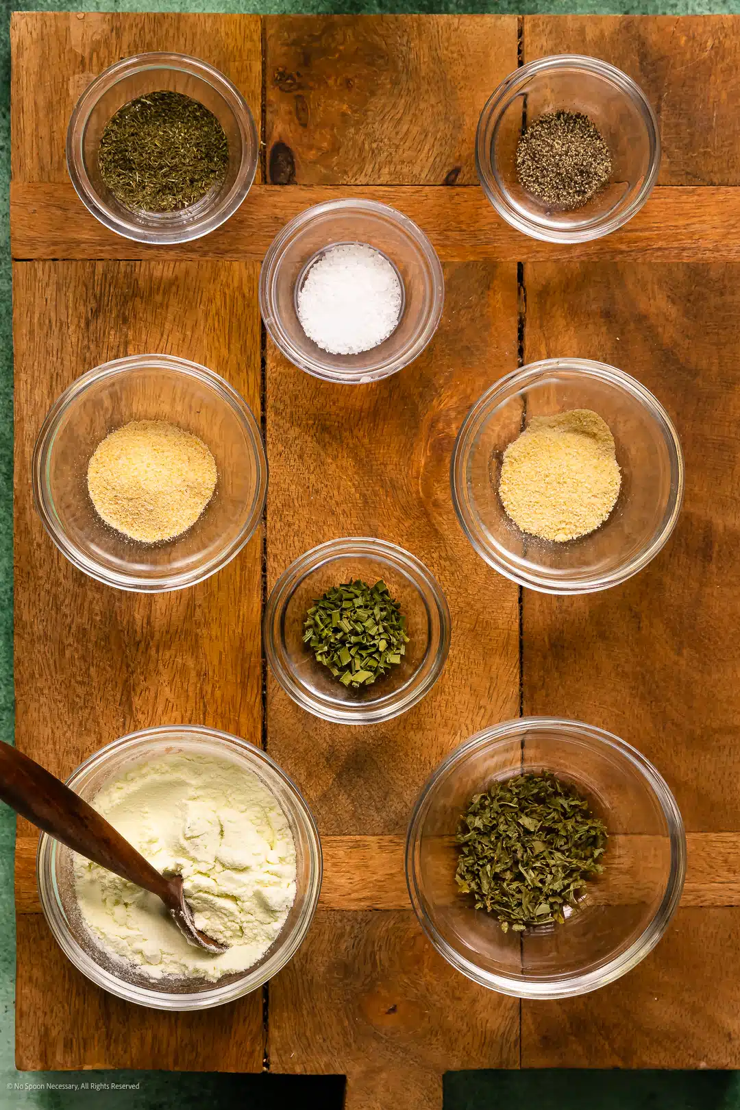 Overhead photo of the eight dry spices in homemade ranch dressing seasoning neatly organized on a kitchen counter.